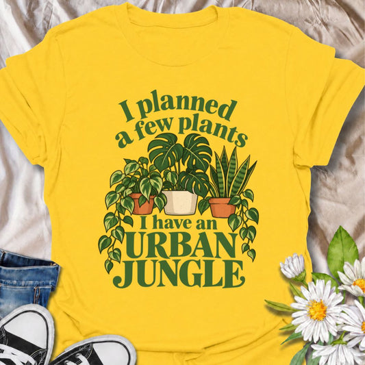 A funny plant T-shirt for anyone who started with a few houseplants and somehow ended up living in an indoor jungle. The phrase “I Planned a Few Plants. I Have an Urban Jungle.” captures the familiar reality of plant collecting with light, relatable humor. Featuring monstera, pothos, and snake plants, this design is perfect for plant parents, houseplant collectors, and indoor gardeners. It makes a great gift for anyone whose shelves, windowsills, and corners have slowly disappeared behind greenery. Perfect 