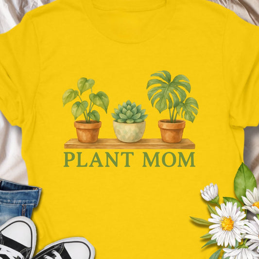Show off your green thumb with this charming “Plant Mom” t-shirt featuring potted plants on a wooden shelf. Ideal for plant lovers, indoor gardeners, or anyone who adores succulents and tropical houseplants. This tee makes a perfect gift for Mother's Day, birthdays, or just to treat yourself with botanical flair.