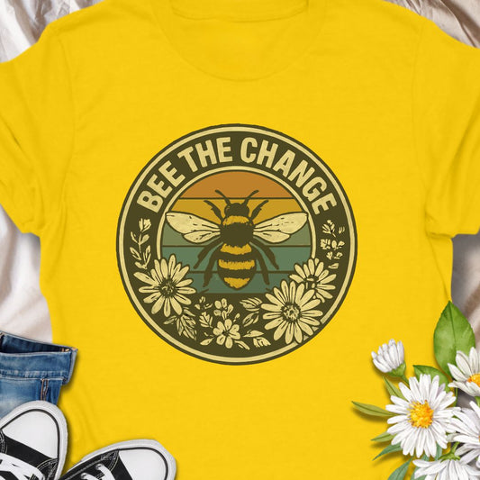 Spread positivity and environmental awareness with this vintage-style “Bee The Change” t-shirt. Featuring a bold bee illustration surrounded by wildflowers and retro sunset colors, it’s perfect for nature lovers, pollinator protectors, and eco-conscious souls. Makes a thoughtful gift for beekeepers, gardeners, or anyone who believes in making a difference—one bee at a time.