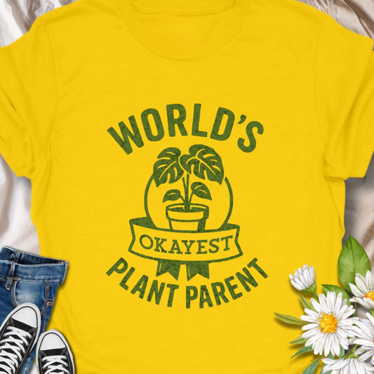 Embrace your perfectly average plant parent status with this tongue-in-cheek shirt. A great gift for honest gardeners and plant lovers.  Soft, lived-in comfort meets playful plant pride. This t-shirt quietly celebrates the small victories of indoor gardening with a hand-drawn, vintage-style graphic reading “World’s Okayest Plant Parent.” 