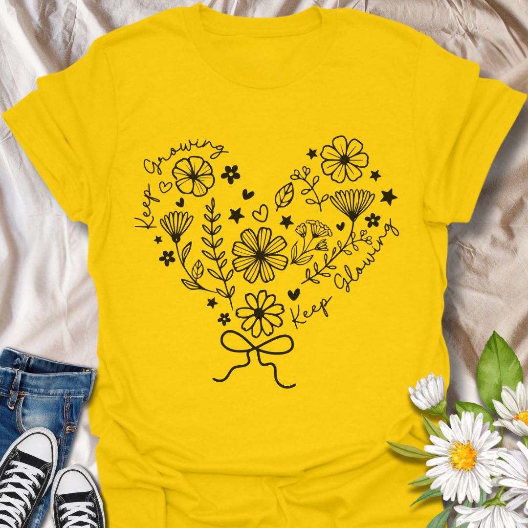 Charming floral heart t-shirt featuring delicate hand-drawn flowers with positive affirmations “Keep Growing, Keep Glowing.” A perfect uplifting gift for gardeners and plant lovers.  Daisy