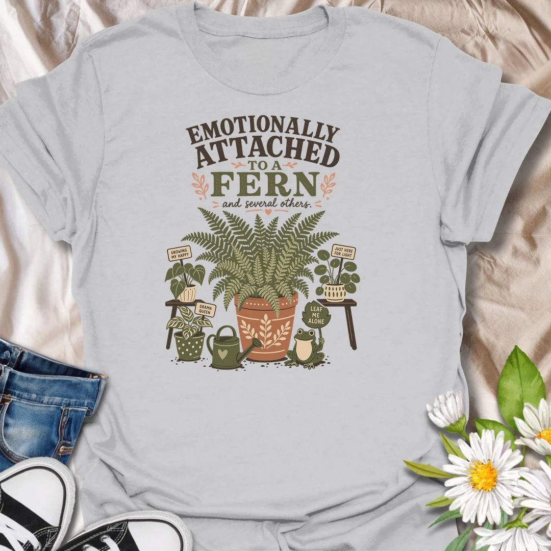Celebrate your favorite leafy companion with this “Emotionally Attached to a Fern” T-shirt. Featuring a large decorative fern, houseplants, a watering can, and a cheerful frog, it is perfect for devoted plant parents. A charming gift for fern lovers, indoor gardeners, and botanical collectors.
