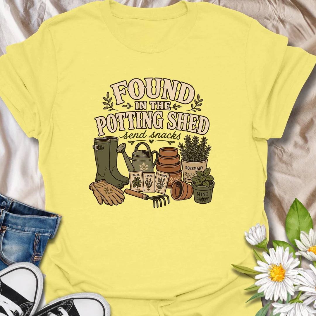 A cozy gardening T-shirt for anyone happiest among pots, herbs, seeds, and soil. The design features gardening boots, a watering can, terracotta pots, seed packets, and fresh herbs. A fun gift for potting shed lovers, herb gardeners, and women who disappear into the garden for hours.