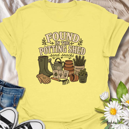 A cozy gardening T-shirt for anyone happiest among pots, herbs, seeds, and soil. The design features gardening boots, a watering can, terracotta pots, seed packets, and fresh herbs. A fun gift for potting shed lovers, herb gardeners, and women who disappear into the garden for hours.