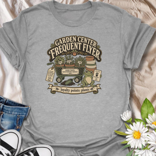 Earn imaginary loyalty points with this funny “Garden Center Frequent Flyer” T-shirt. Featuring a plant-filled cart, herb pots, garden supplies, and a cheerful frog, it is made for anyone who never leaves the nursery empty-handed. A playful gift for plant shoppers and enthusiastic gardeners.
