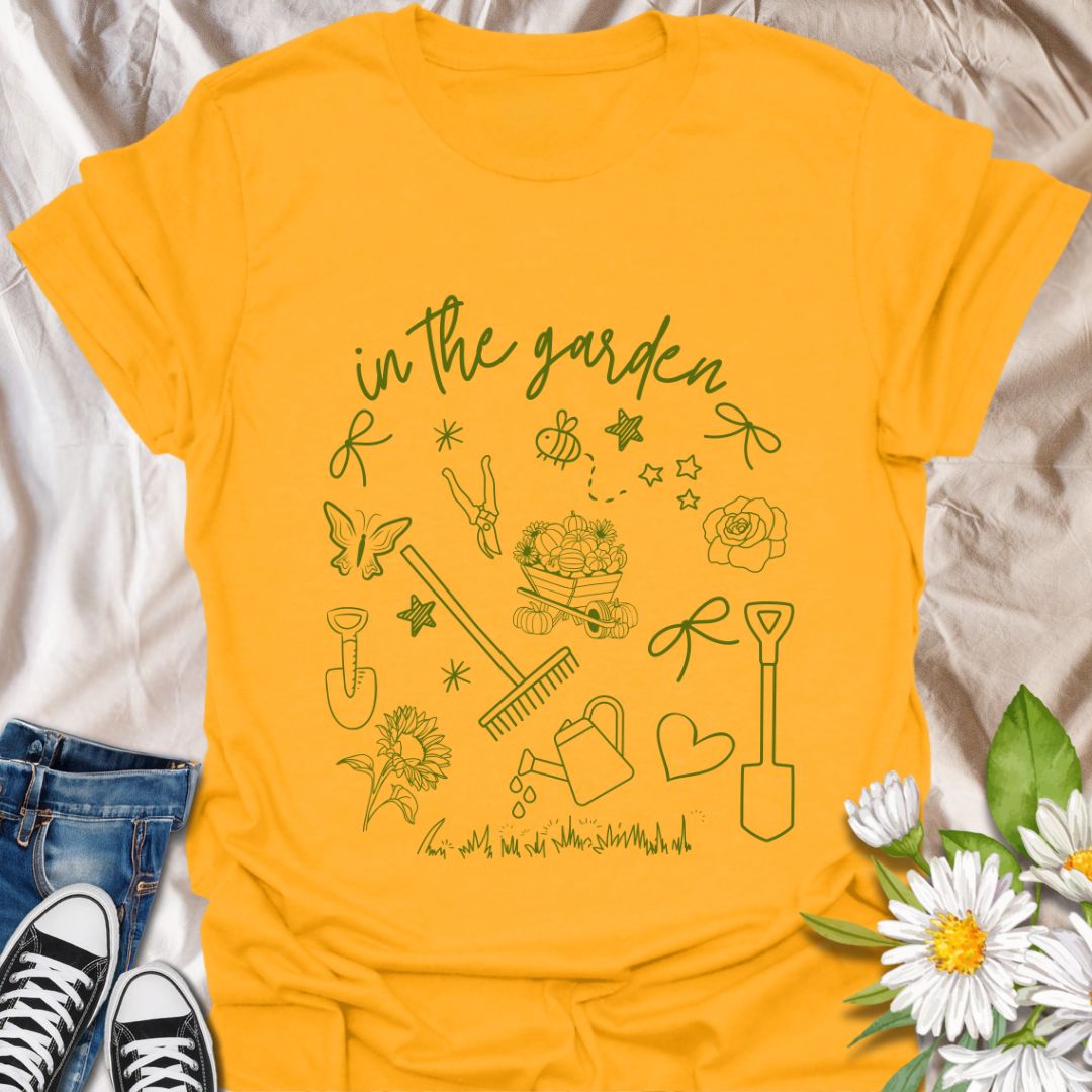 Charming "In The Garden" doodle style t-shirt with hand-drawn gardening tools, flowers, and butterflies. Perfect gift for gardeners, plant lovers, and nature enthusiasts. Stylish botanical apparel for spring, summer, or everyday wear. Celebrate your green thumb!