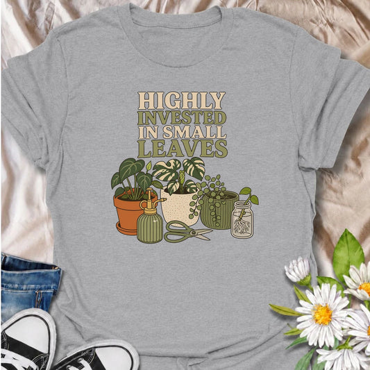 A funny houseplant T-shirt for plant lovers who are highly invested in every new leaf, cutting, and tiny bit of growth. Featuring a collection of potted plants, propagation supplies, and gardening tools, this design is perfect for dedicated plant parents and indoor gardeners. The “Highly Invested in Small Leaves” phrase captures the slightly obsessive joy of watching houseplants grow. It makes a great gift for pothos lovers, propagation fans, and anyone building their own indoor jungle. A relaxed botanical 