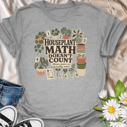 Plant numbers are always negotiable with this “Houseplant Math Doesn’t Count” T-shirt. Surrounded by numbered plants, decorative pots, cuttings, and a suspiciously long receipt, the design is perfect for enthusiastic indoor gardeners. It makes a funny gift for plant collectors who believe three more is basically none.