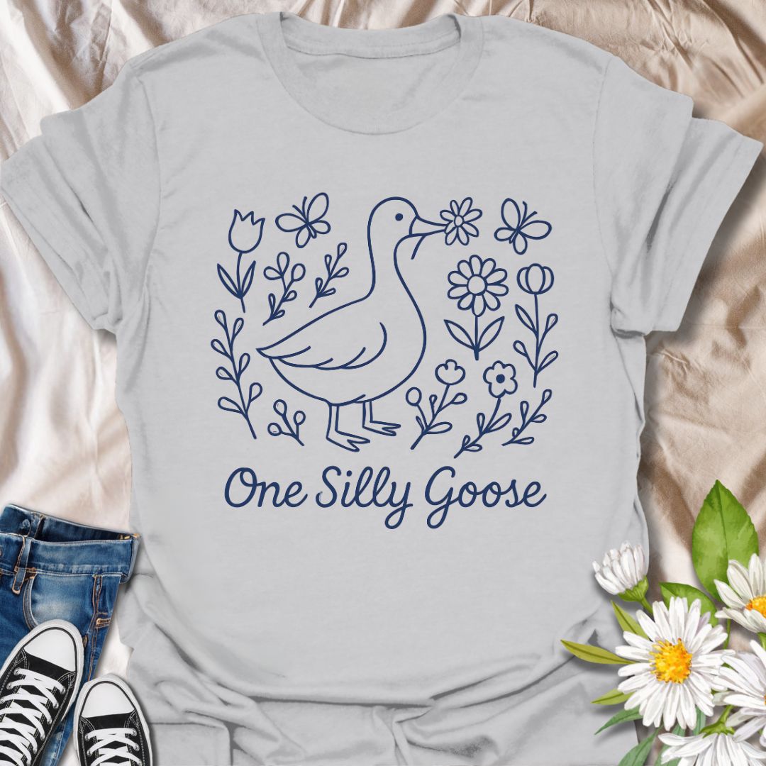 Adorable ‘One Silly Goose’ shirt with a playful goose surrounded by flowers and butterflies. Perfect for humor lovers, goose enthusiasts, and whimsical nature apparel fans.