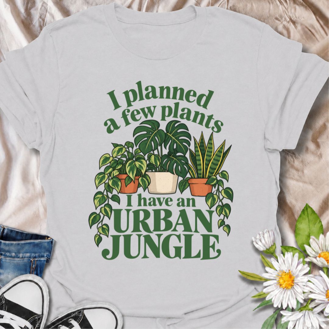 A funny plant T-shirt for anyone who started with a few houseplants and somehow ended up living in an indoor jungle. The phrase “I Planned a Few Plants. I Have an Urban Jungle.” captures the familiar reality of plant collecting with light, relatable humor. Featuring monstera, pothos, and snake plants, this design is perfect for plant parents, houseplant collectors, and indoor gardeners. It makes a great gift for anyone whose shelves, windowsills, and corners have slowly disappeared behind greenery. Perfect 