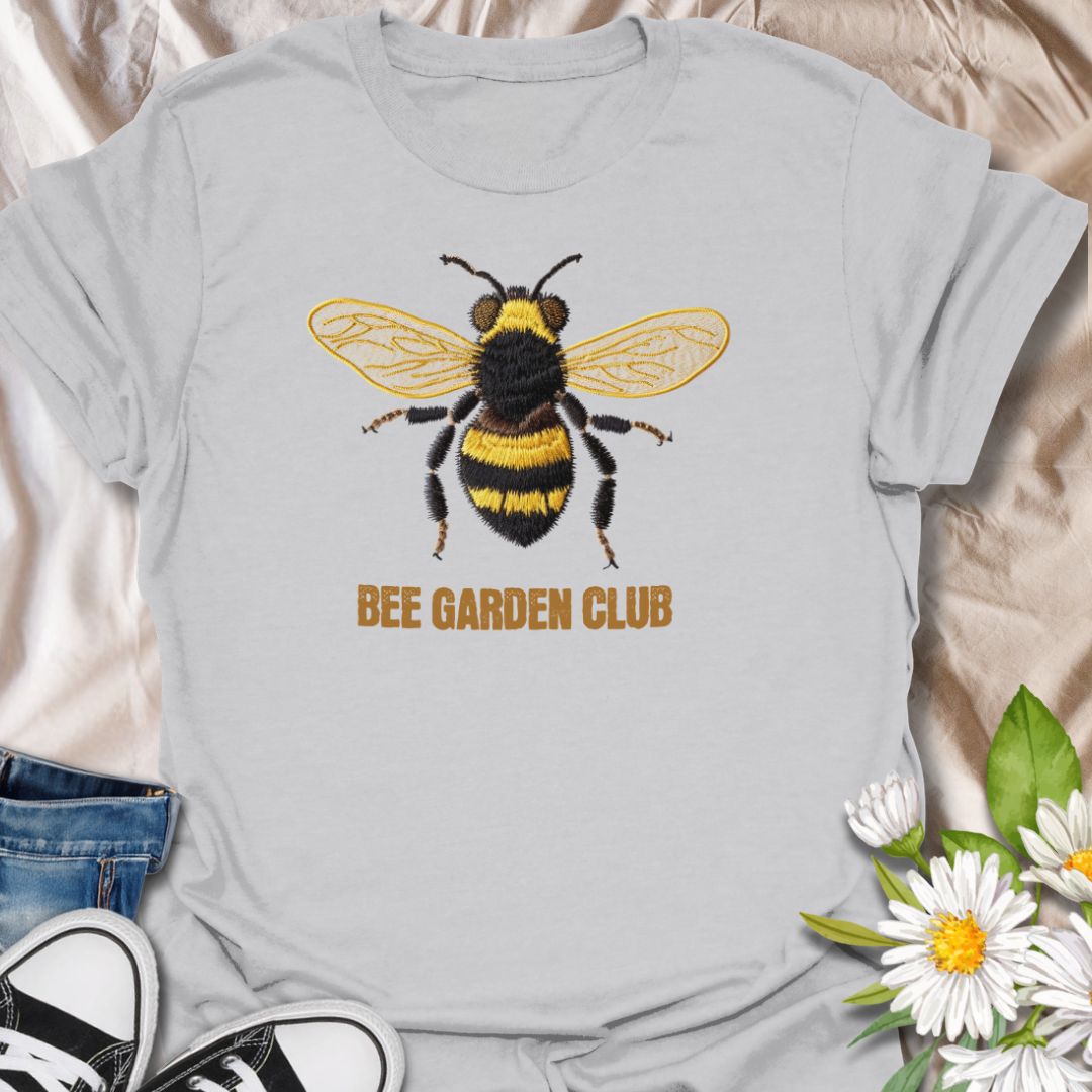 This Bee Garden Club t-shirt is made for gardeners, pollinator lovers, and nature fans who want a simple bee design with a refined botanical feel. Featuring a detailed faux-embroidered bee with golden wings, fuzzy black and yellow stripes, and clean Bee Garden Club lettering, this design has a classic garden-club look that is easy to wear. Perfect for bee lovers, gardeners, wildflower fans, pollinator supporters, nature lovers, and anyone who wants to celebrate the garden’s hardest little workers.