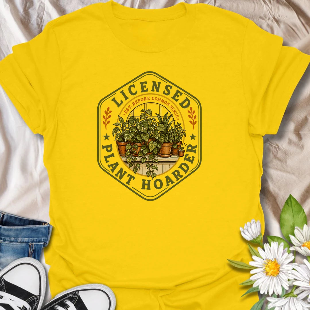 This Licensed Plant Hoarder t-shirt is made for houseplant lovers who ran out of space long before they ran out of excuses. Featuring a vintage badge-style design with an overcrowded windowsill full of potted plants, trailing vines, and the phrase Est. Before Common Sense, this tee has a funny plant-collector feel with classic botanical charm. Perfect for plant moms, plant dads, indoor gardeners, houseplant collectors, propagation fans, and anyone proudly licensed to bring home just one more plant.