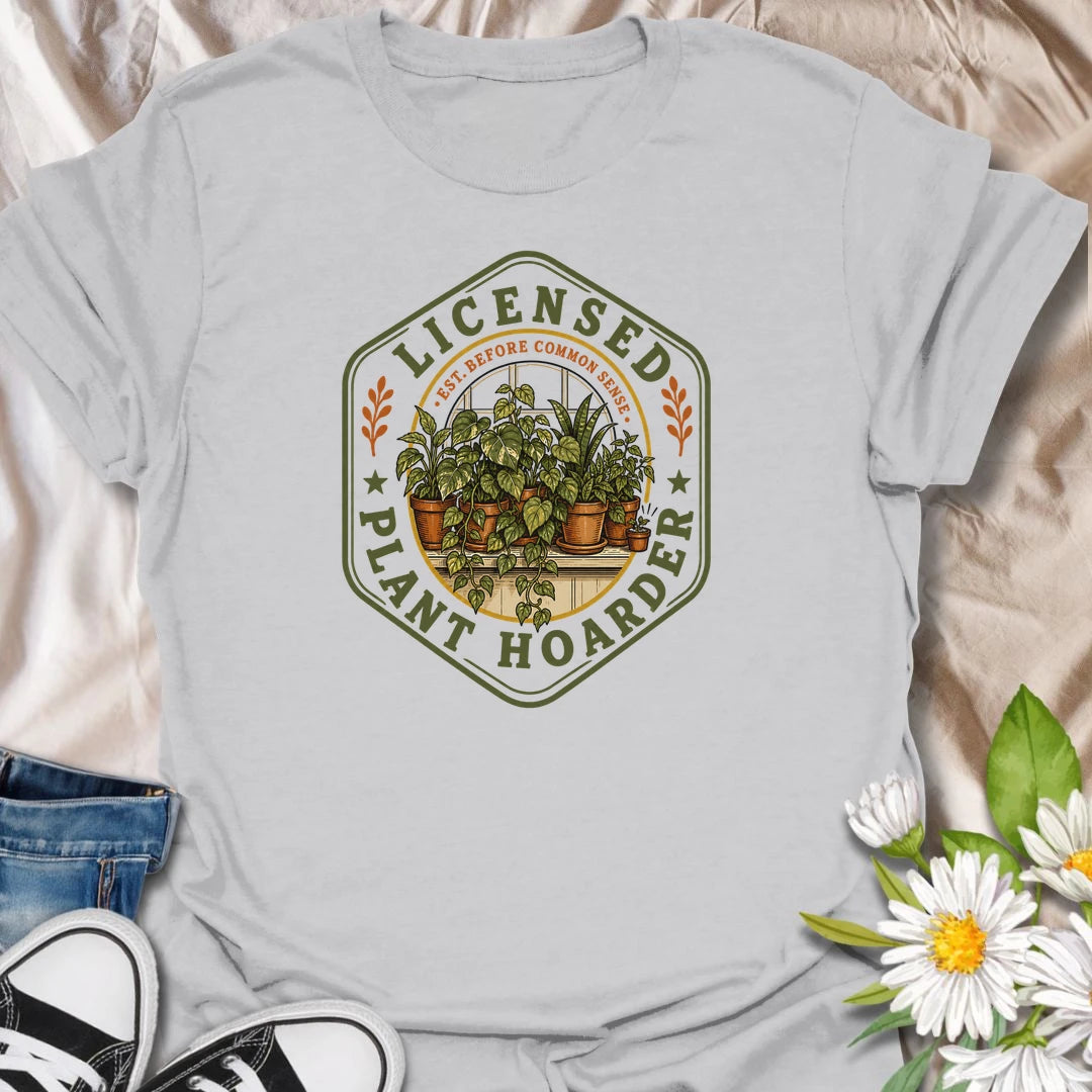 This Licensed Plant Hoarder t-shirt is made for houseplant lovers who ran out of space long before they ran out of excuses. Featuring a vintage badge-style design with an overcrowded windowsill full of potted plants, trailing vines, and the phrase Est. Before Common Sense, this tee has a funny plant-collector feel with classic botanical charm. Perfect for plant moms, plant dads, indoor gardeners, houseplant collectors, propagation fans, and anyone proudly licensed to bring home just one more plant.