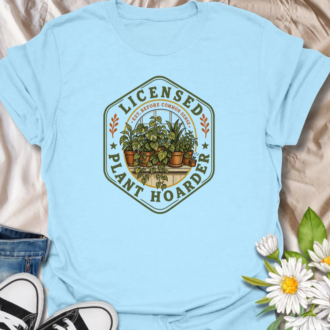 This Licensed Plant Hoarder t-shirt is made for houseplant lovers who ran out of space long before they ran out of excuses. Featuring a vintage badge-style design with an overcrowded windowsill full of potted plants, trailing vines, and the phrase Est. Before Common Sense, this tee has a funny plant-collector feel with classic botanical charm. Perfect for plant moms, plant dads, indoor gardeners, houseplant collectors, propagation fans, and anyone proudly licensed to bring home just one more plant.