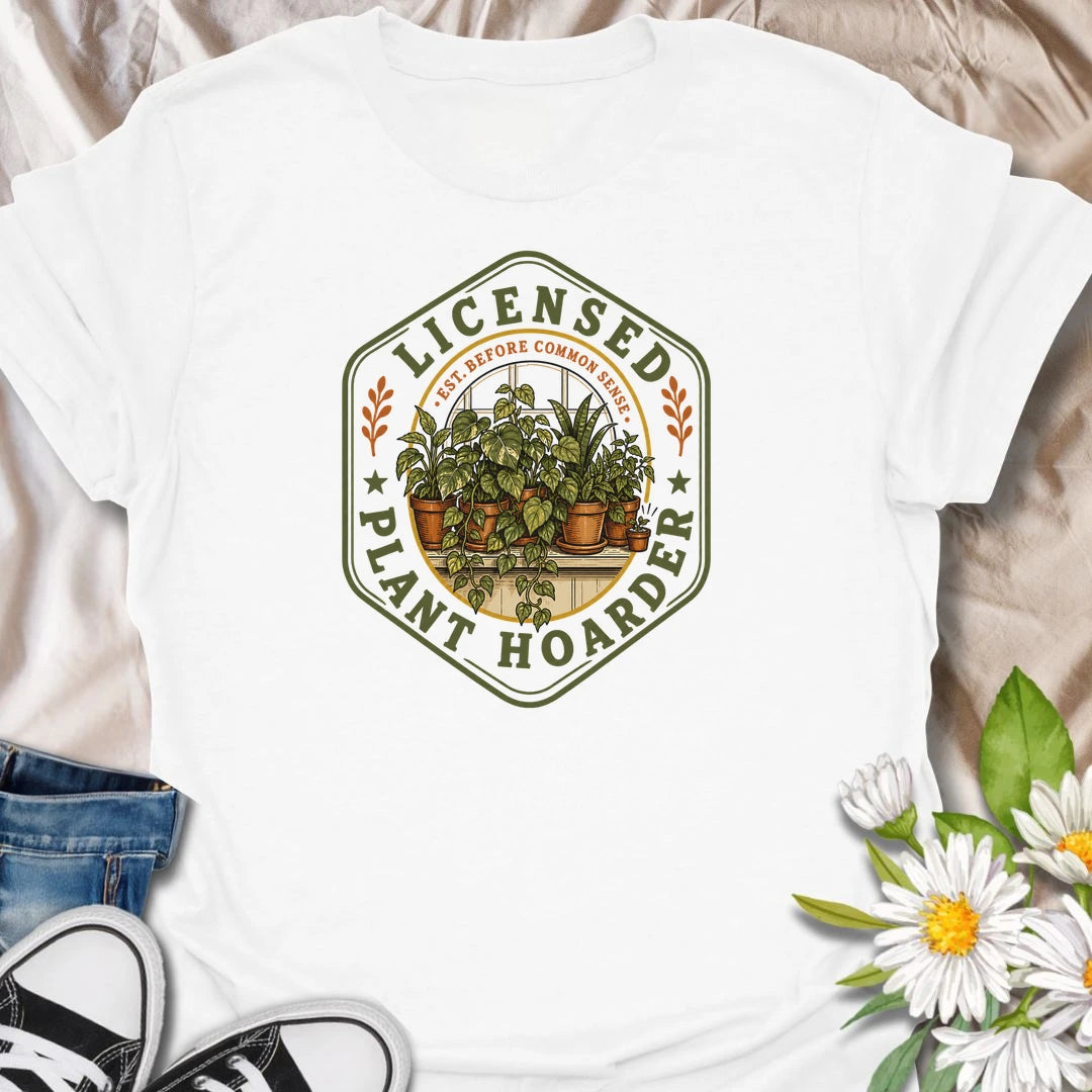 This Licensed Plant Hoarder t-shirt is made for houseplant lovers who ran out of space long before they ran out of excuses. Featuring a vintage badge-style design with an overcrowded windowsill full of potted plants, trailing vines, and the phrase Est. Before Common Sense, this tee has a funny plant-collector feel with classic botanical charm. Perfect for plant moms, plant dads, indoor gardeners, houseplant collectors, propagation fans, and anyone proudly licensed to bring home just one more plant.