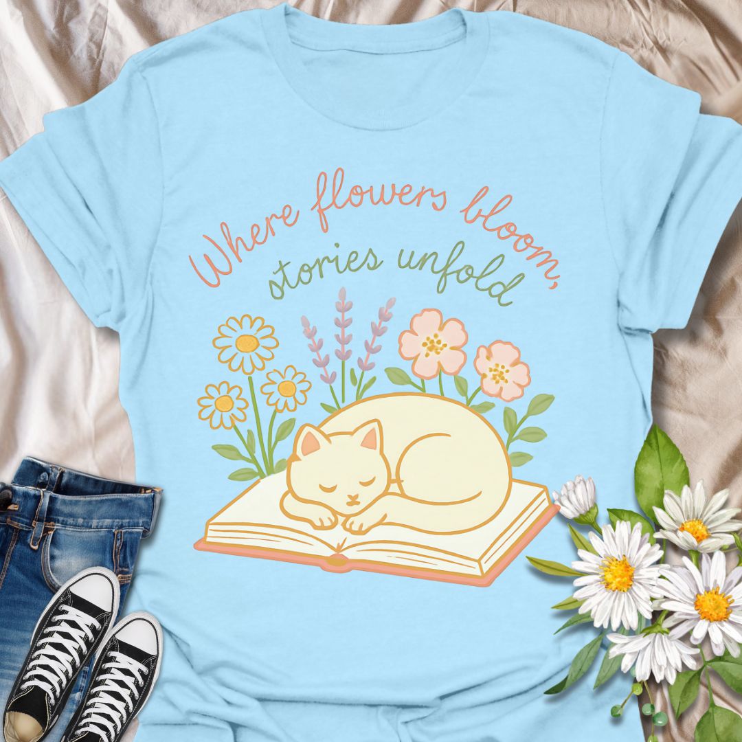 Cozy cat and book t-shirt with pastel flowers and the quote 'Where flowers bloom, stories unfold.' Perfect for book lovers, cat moms, gardeners, and daydreamers who adore cottagecore and literary aesthetics. Soft and sweet tee ideal for spring, reading nooks, and gifting.