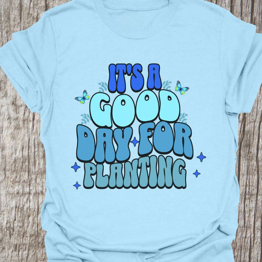 It's a good day for planting written in various shades of blue text with small stars and buterflies decorating it, on a light blue t-shirt