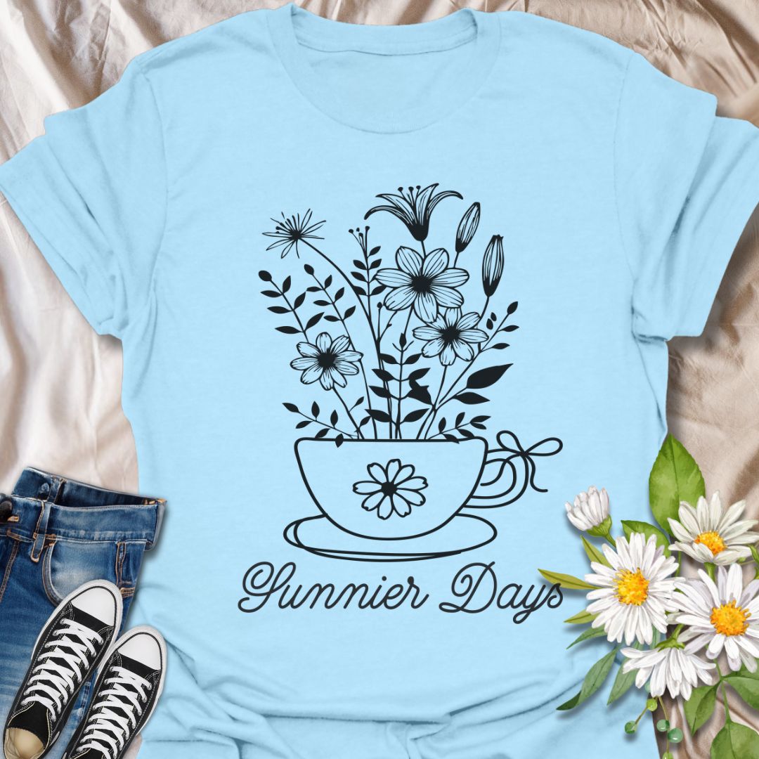 Charming floral t-shirt featuring hand-drawn white flowers blooming from a teacup with the words “Sunnier Days.” A cozy, uplifting design for flower lovers, tea drinkers, and anyone who embraces the simple joys of life. Great gift for gardeners and sunny souls.