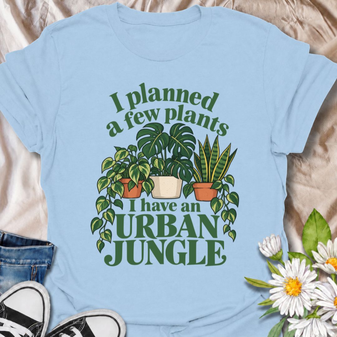 A funny plant T-shirt for anyone who started with a few houseplants and somehow ended up living in an indoor jungle. The phrase “I Planned a Few Plants. I Have an Urban Jungle.” captures the familiar reality of plant collecting with light, relatable humor. Featuring monstera, pothos, and snake plants, this design is perfect for plant parents, houseplant collectors, and indoor gardeners. It makes a great gift for anyone whose shelves, windowsills, and corners have slowly disappeared behind greenery. Perfect 