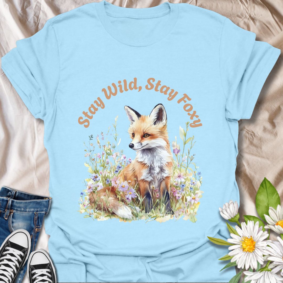 Charming t-shirt featuring a fox sitting among wildflowers with “Stay Wild, Stay Foxy” quote. Perfect gift for animal lovers, nature enthusiasts, and wildlife fans who adore foxes, woodland creatures, floral art, and playful outdoor vibes.