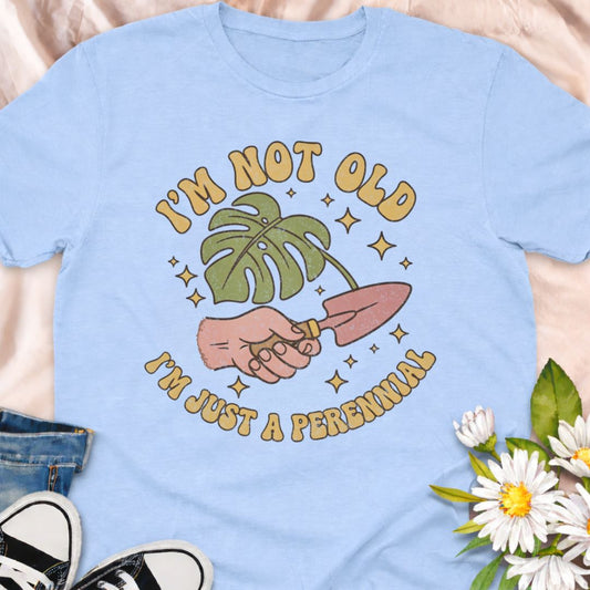 Funny gardening t-shirt featuring a whimsical frog riding a bike with flowers, seeds, and pots, plus the phrase “Off to Cause a Garden Kerfuffle.” Perfect for gardeners, plant lovers, frog fans, and cottagecore garden style lovers.