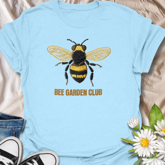 This Bee Garden Club t-shirt is made for gardeners, pollinator lovers, and nature fans who want a simple bee design with a refined botanical feel. Featuring a detailed faux-embroidered bee with golden wings, fuzzy black and yellow stripes, and clean Bee Garden Club lettering, this design has a classic garden-club look that is easy to wear. Perfect for bee lovers, gardeners, wildflower fans, pollinator supporters, nature lovers, and anyone who wants to celebrate the garden’s hardest little workers.