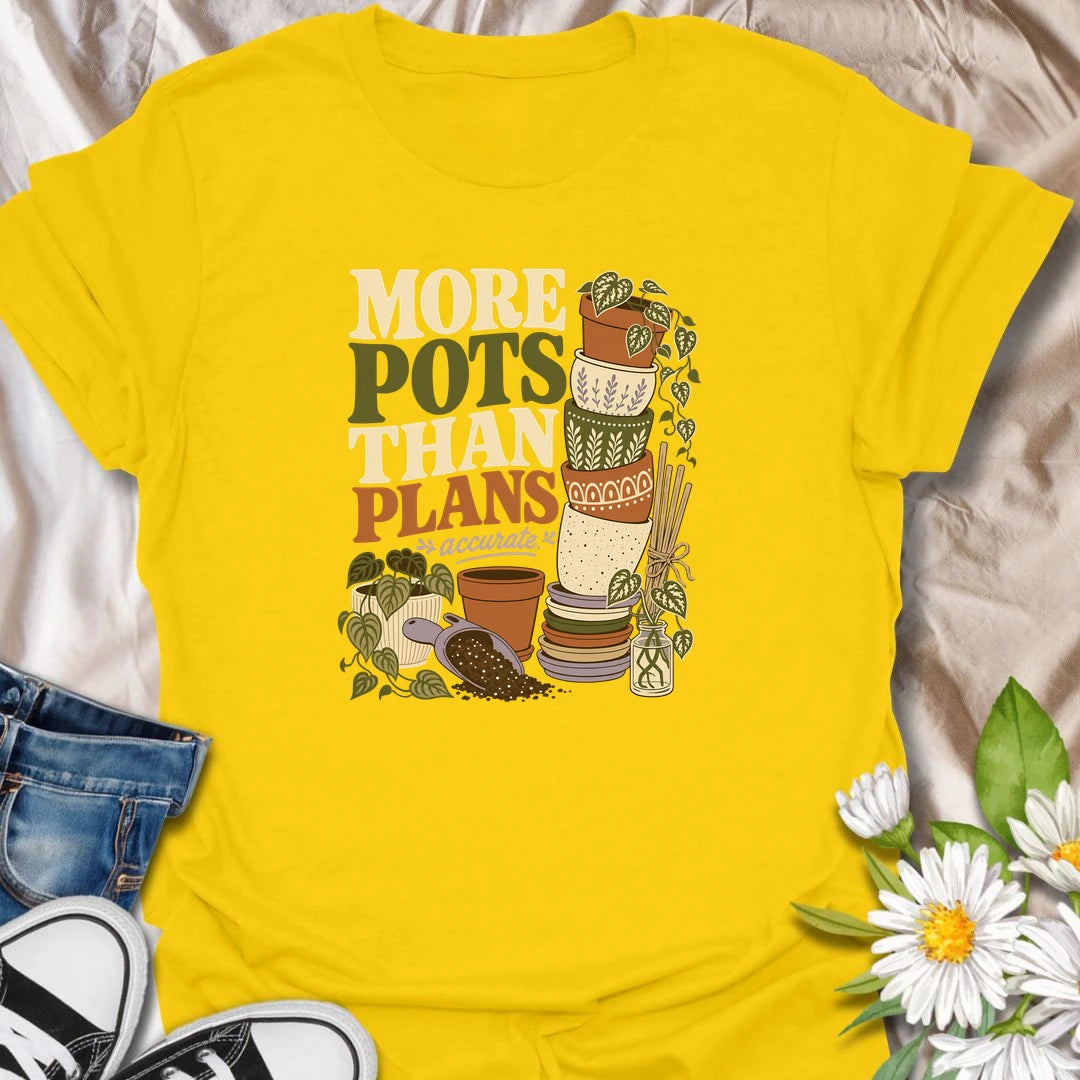 A relatable plant lover T-shirt for anyone whose pot collection has grown faster than their planting plans. The design features a tall stack of decorative pots, trailing houseplants, propagation cuttings, and potting soil. A fun gift for gardeners, plant collectors, and anyone who can never resist another beautiful planter.