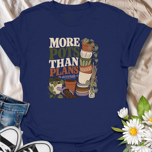 A relatable plant lover T-shirt for anyone whose pot collection has grown faster than their planting plans. The design features a tall stack of decorative pots, trailing houseplants, propagation cuttings, and potting soil. A fun gift for gardeners, plant collectors, and anyone who can never resist another beautiful planter.