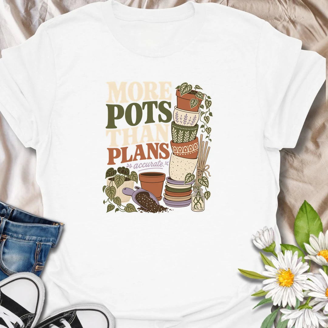 A relatable plant lover T-shirt for anyone whose pot collection has grown faster than their planting plans. The design features a tall stack of decorative pots, trailing houseplants, propagation cuttings, and potting soil. A fun gift for gardeners, plant collectors, and anyone who can never resist another beautiful planter.
