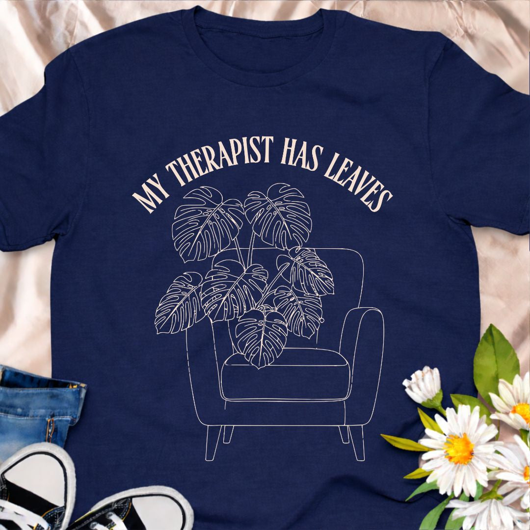 For plant people who spill their heart out to their houseplants, this “My Therapist Has Leaves” t-shirt says it all. Features a cozy armchair and lush monstera, making it the perfect aesthetic plant lover tee for self-care days.