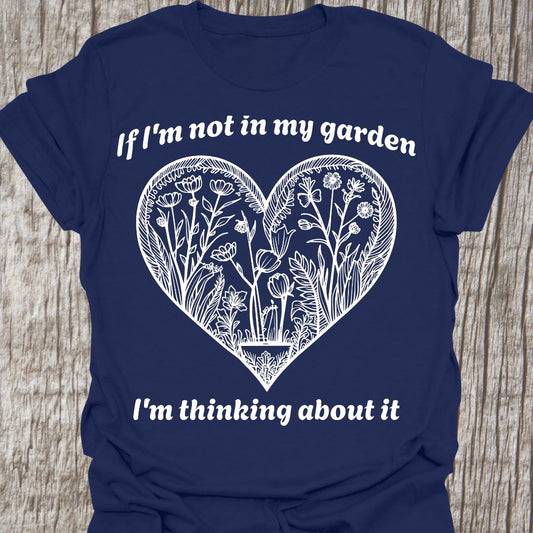 Text in white around a heart shape which contains flower images in white.  Phrase above the heart is 'if I'm not in my garden' and below the heart 'I'm thinking about it', on a navy t-shirt