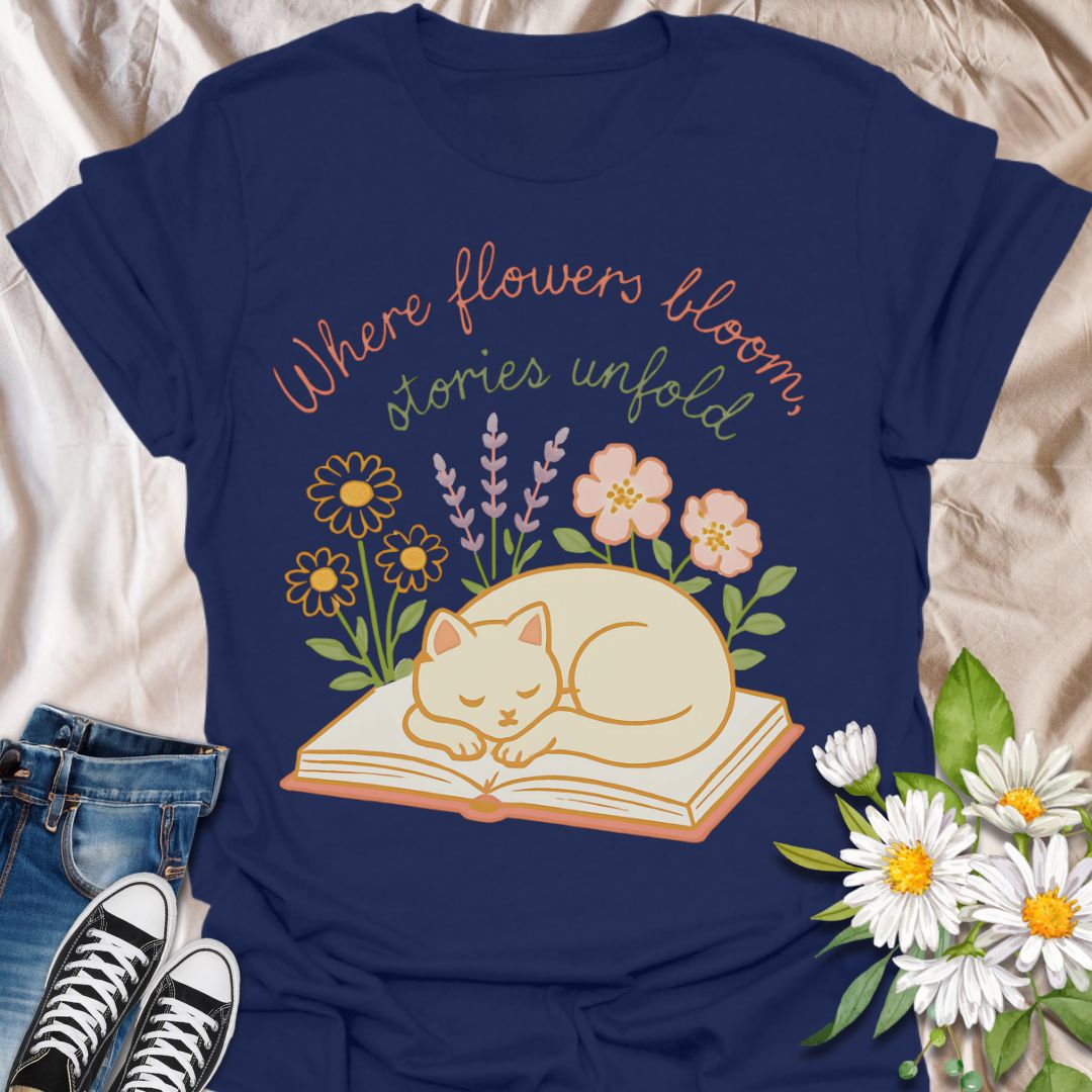 Cozy cat and book t-shirt with pastel flowers and the quote 'Where flowers bloom, stories unfold.' Perfect for book lovers, cat moms, gardeners, and daydreamers who adore cottagecore and literary aesthetics. Soft and sweet tee ideal for spring, reading nooks, and gifting.
