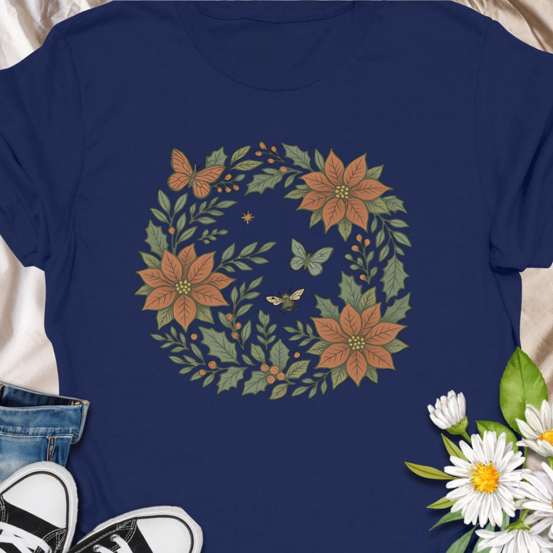 Festive botanical tee featuring a Christmas wreath with poinsettias, bees, and butterflies. Perfect holiday wear for plant lovers.