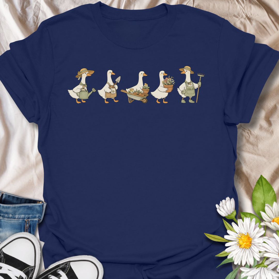 This Gardening Geese t-shirt is made for gardeners, plant lovers, and anyone who enjoys cute nature-inspired artwork with a little humor. Featuring a row of charming geese carrying watering cans, garden tools, flower pots, a wheelbarrow, and fresh plants, this design has a playful cottagecore garden feel that is easy to wear. Perfect for gardeners, duck lovers, plant moms, flower fans, backyard growers, and anyone who thinks garden chores are better with a gaggle of helpful Geese.