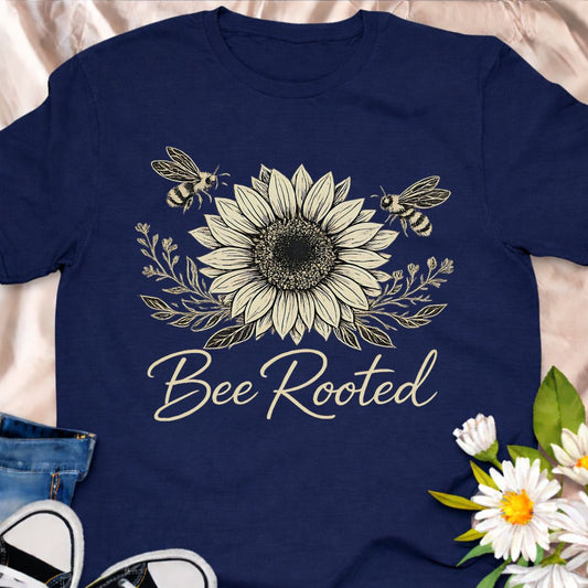 Celebrate slow living and nature connection with this Bee Rooted botanical t-shirt. Featuring a detailed sunflower illustration with bees, this nature-inspired tee is perfect for gardeners, pollinator lovers, and eco-minded souls who believe in staying grounded and growing with purpose.