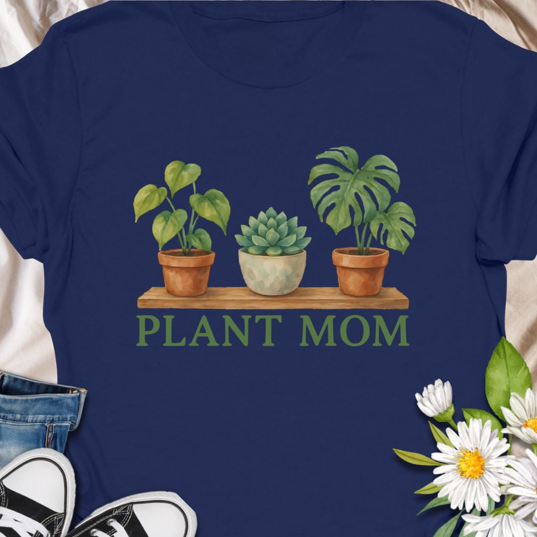 Show off your green thumb with this charming “Plant Mom” t-shirt featuring potted plants on a wooden shelf. Ideal for plant lovers, indoor gardeners, or anyone who adores succulents and tropical houseplants. This tee makes a perfect gift for Mother's Day, birthdays, or just to treat yourself with botanical flair.