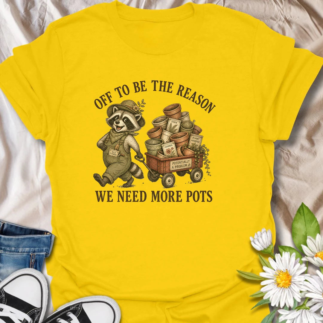 This Off To Be The Reason We Need More Pots t-shirt is perfect for gardeners and plant lovers who always have another plant, cutting, or seedling waiting for a home. Featuring a cheerful raccoon with a wagon full of flower pots, seed packets, and garden supplies, this funny botanical design is great for plant moms, houseplant collectors, gardeners, and anyone who can never have too many pots.