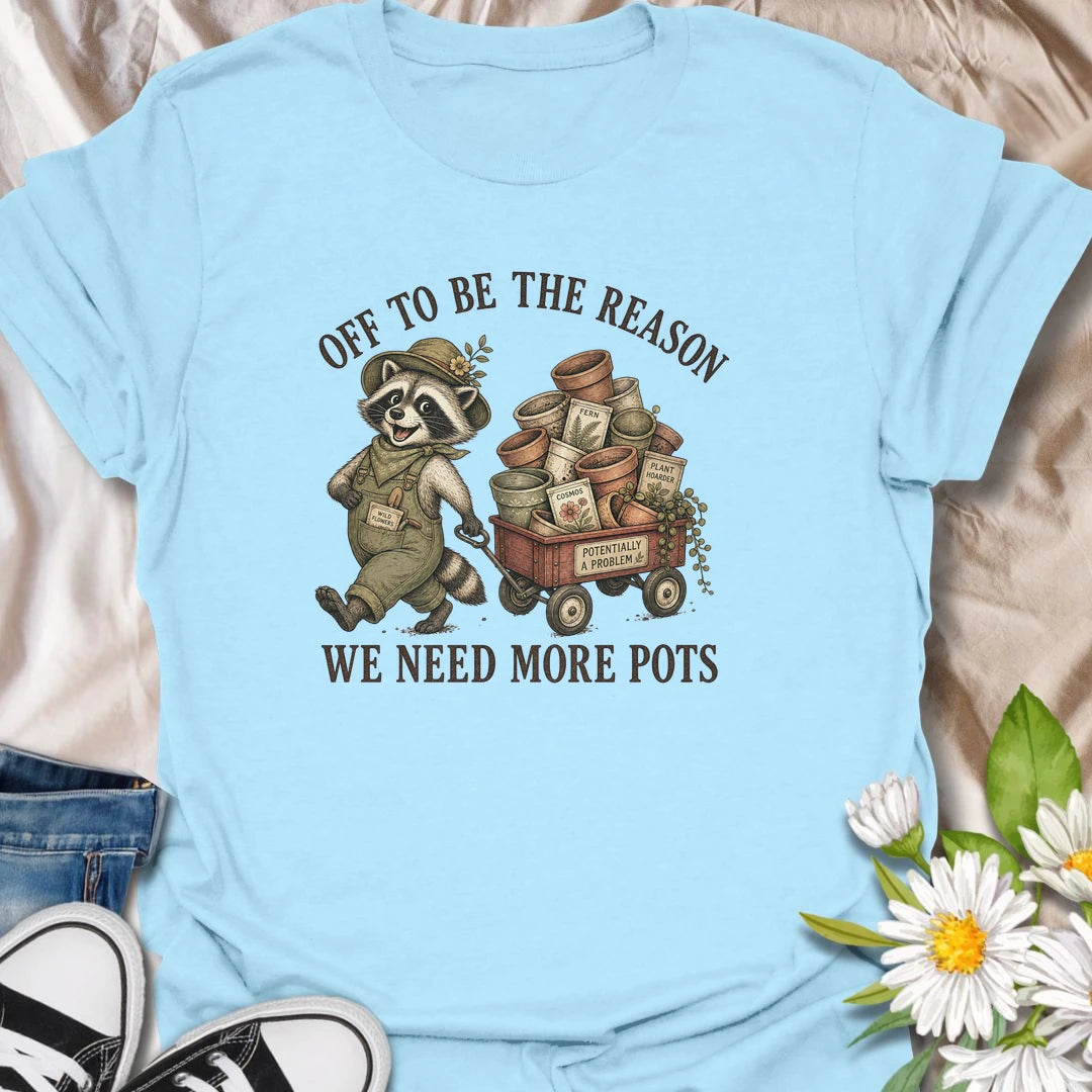 This Off To Be The Reason We Need More Pots t-shirt is perfect for gardeners and plant lovers who always have another plant, cutting, or seedling waiting for a home. Featuring a cheerful raccoon with a wagon full of flower pots, seed packets, and garden supplies, this funny botanical design is great for plant moms, houseplant collectors, gardeners, and anyone who can never have too many pots.