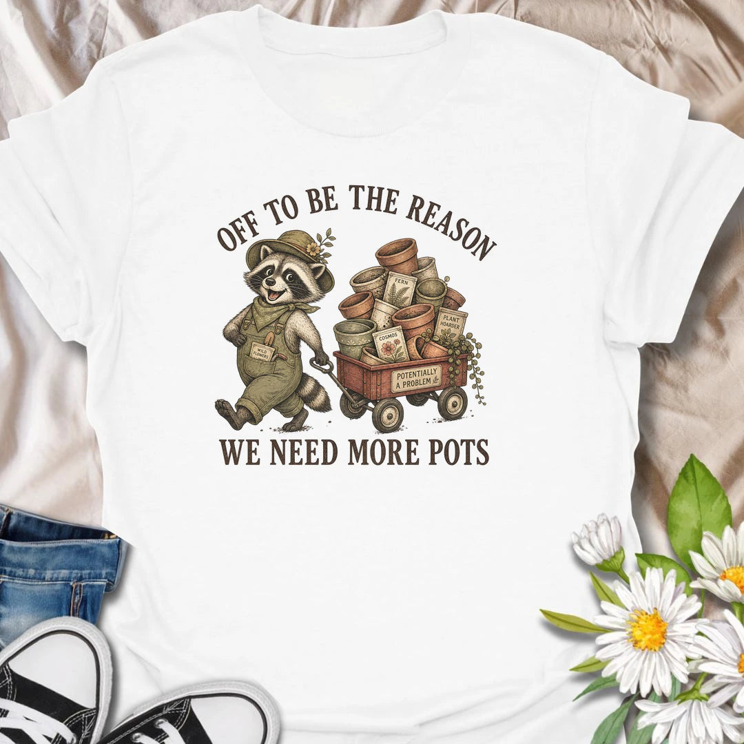 This Off To Be The Reason We Need More Pots t-shirt is perfect for gardeners and plant lovers who always have another plant, cutting, or seedling waiting for a home. Featuring a cheerful raccoon with a wagon full of flower pots, seed packets, and garden supplies, this funny botanical design is great for plant moms, houseplant collectors, gardeners, and anyone who can never have too many pots.