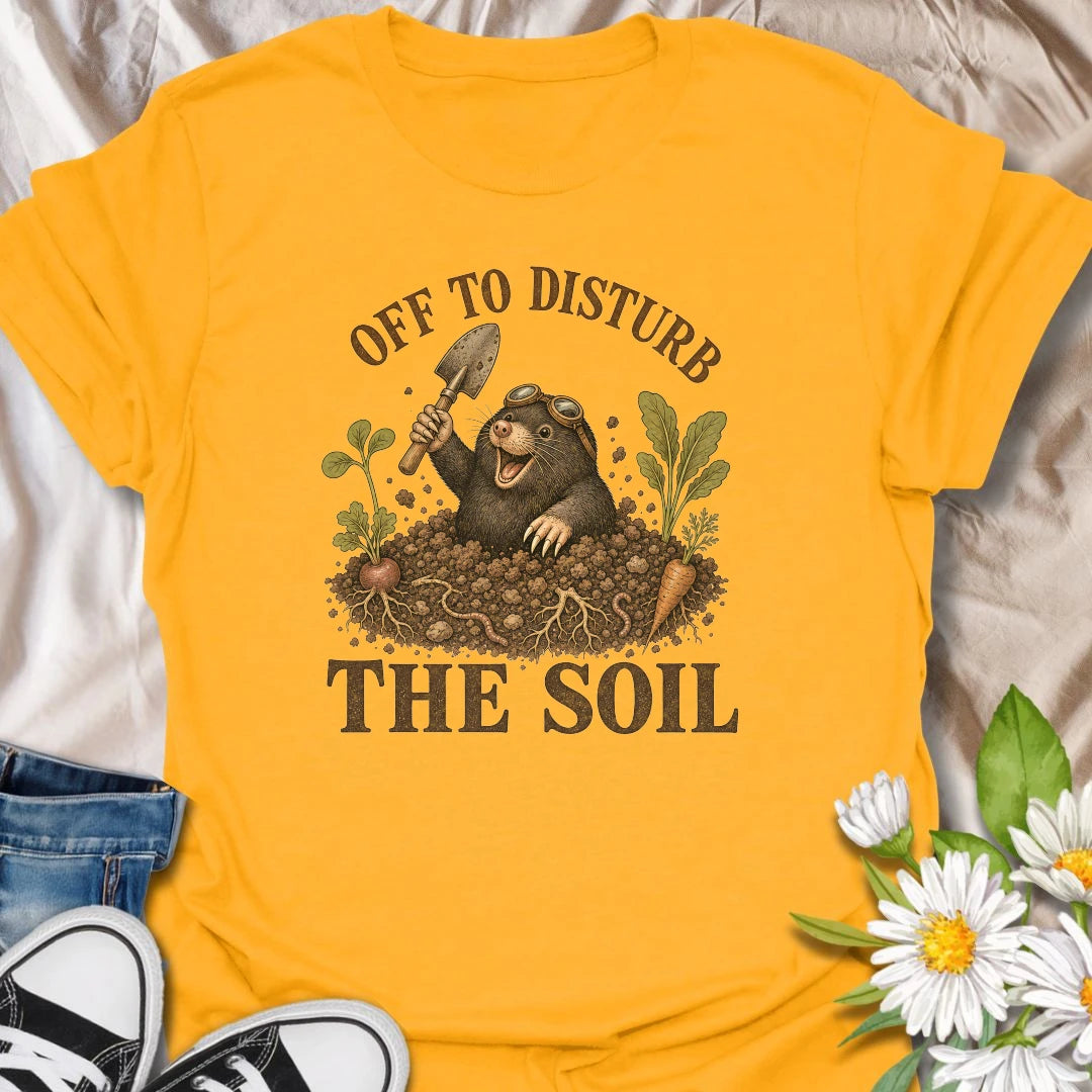 This Off To Disturb The Soil t-shirt is perfect for gardeners who love digging, planting, and making a little mess in the dirt. Featuring a happy mole popping out of the soil with a garden trowel, vegetables, roots, and earthy details, this funny gardening design is great for backyard growers, vegetable gardeners, plant lovers, and anyone who enjoys getting their hands dirty.