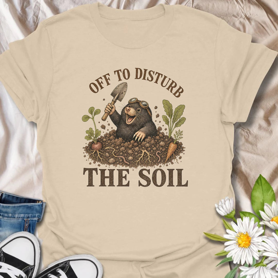 This Off To Disturb The Soil t-shirt is perfect for gardeners who love digging, planting, and making a little mess in the dirt. Featuring a happy mole popping out of the soil with a garden trowel, vegetables, roots, and earthy details, this funny gardening design is great for backyard growers, vegetable gardeners, plant lovers, and anyone who enjoys getting their hands dirty.