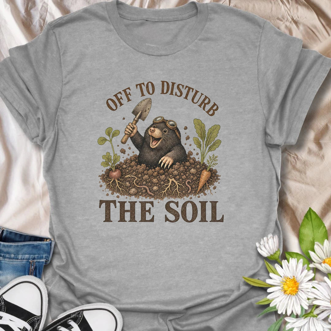 This Off To Disturb The Soil t-shirt is perfect for gardeners who love digging, planting, and making a little mess in the dirt. Featuring a happy mole popping out of the soil with a garden trowel, vegetables, roots, and earthy details, this funny gardening design is great for backyard growers, vegetable gardeners, plant lovers, and anyone who enjoys getting their hands dirty.