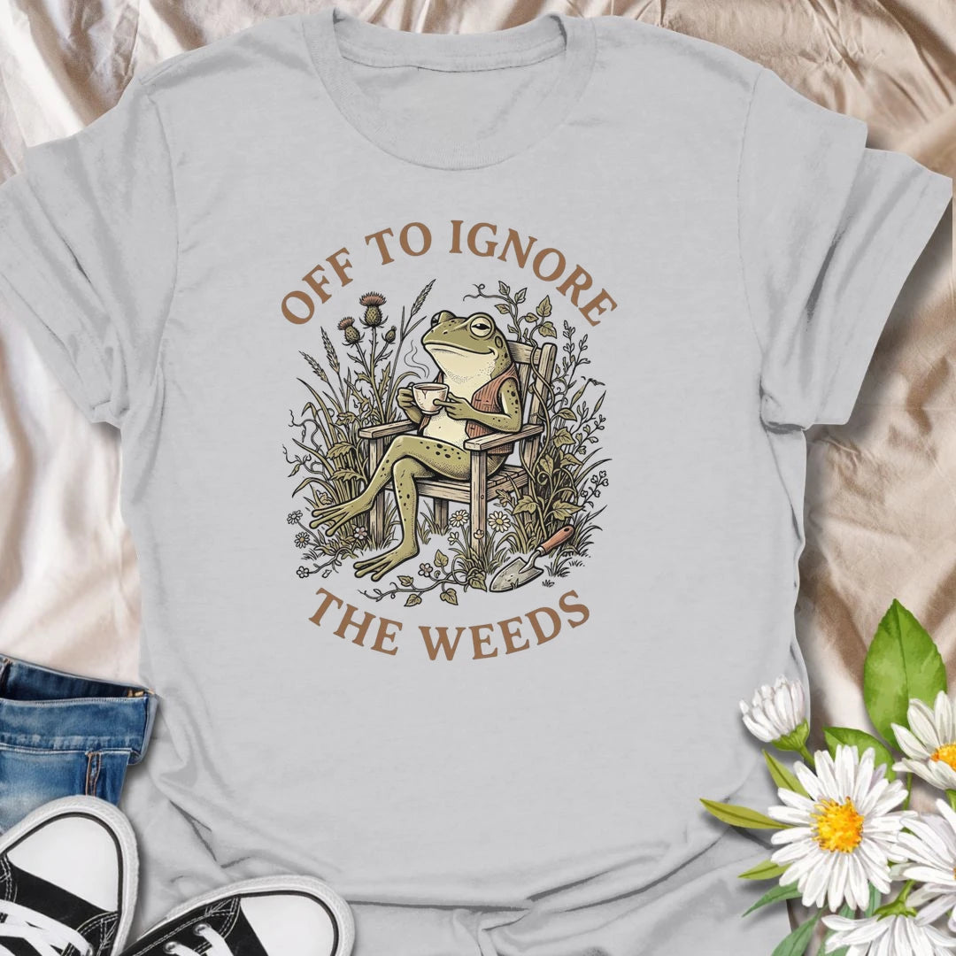 This Off To Ignore The Weeds t-shirt is perfect for gardeners who love the garden but are not always rushing to pull every weed. Featuring a relaxed frog sitting in a garden chair surrounded by plants, flowers, and overgrown greenery, this funny botanical design is great for plant lovers, backyard gardeners, cottage garden fans, frog lovers, and anyone who believes weeds can wait.
