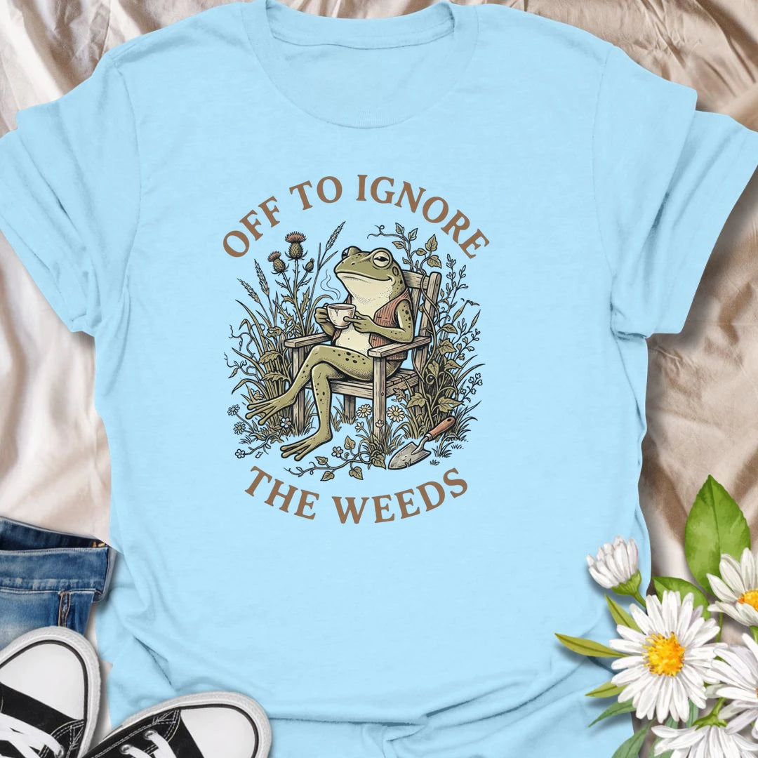 This Off To Ignore The Weeds t-shirt is perfect for gardeners who love the garden but are not always rushing to pull every weed. Featuring a relaxed frog sitting in a garden chair surrounded by plants, flowers, and overgrown greenery, this funny botanical design is great for plant lovers, backyard gardeners, cottage garden fans, frog lovers, and anyone who believes weeds can wait.
