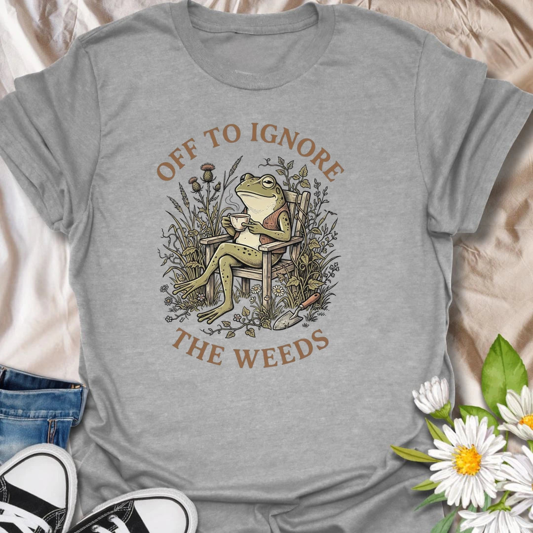 This Off To Ignore The Weeds t-shirt is perfect for gardeners who love the garden but are not always rushing to pull every weed. Featuring a relaxed frog sitting in a garden chair surrounded by plants, flowers, and overgrown greenery, this funny botanical design is great for plant lovers, backyard gardeners, cottage garden fans, frog lovers, and anyone who believes weeds can wait.