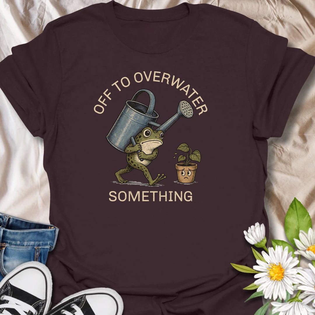 This Off To Overwater Something t-shirt is perfect for plant lovers who know their watering can is both a tool and a potential threat. Featuring a determined frog carrying a big watering can toward a worried potted plant, this funny houseplant design is great for plant moms, plant dads, beginner plant parents, indoor gardeners, and anyone who loves their plants a little too enthusiastically.