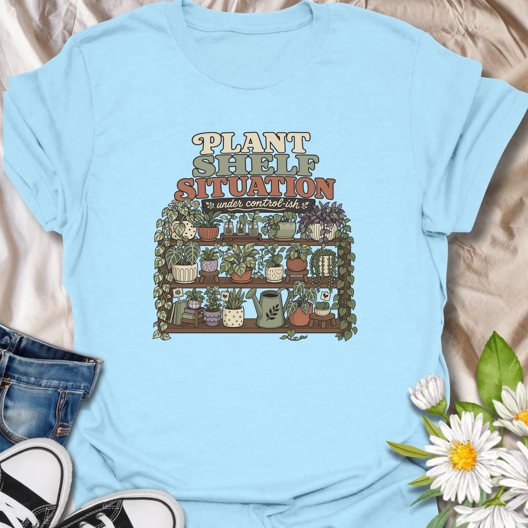 Celebrate a gloriously crowded indoor jungle with this funny “Plant Shelf Situation” T-shirt. Featuring shelves packed with trailing houseplants, decorative pots, propagation jars, and a watering can, it perfectly captures a collection that is only “under control-ish.” A fun gift for plant moms, houseplant collectors, and anyone who always finds room for one more plant.