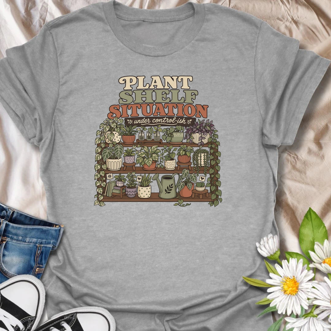 Celebrate a gloriously crowded indoor jungle with this funny “Plant Shelf Situation” T-shirt. Featuring shelves packed with trailing houseplants, decorative pots, propagation jars, and a watering can, it perfectly captures a collection that is only “under control-ish.” A fun gift for plant moms, houseplant collectors, and anyone who always finds room for one more plant.
