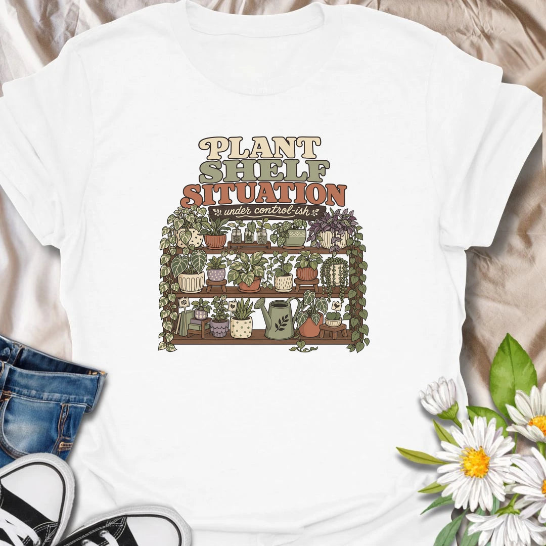Celebrate a gloriously crowded indoor jungle with this funny “Plant Shelf Situation” T-shirt. Featuring shelves packed with trailing houseplants, decorative pots, propagation jars, and a watering can, it perfectly captures a collection that is only “under control-ish.” A fun gift for plant moms, houseplant collectors, and anyone who always finds room for one more plant.