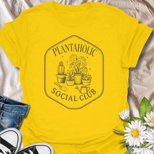 Plantaholic Social Club t-shirt for houseplant collectors who proudly admit the plant obsession is real.
The badge-style design with potted plants, tools, and vintage lettering gives it a fun club-member feel.
It is perfect for plant moms, indoor gardeners, and anyone whose social life includes checking new leaves.
A great gift for plant lovers who belong in a club made entirely of leafy friends and fellow plant addicts.